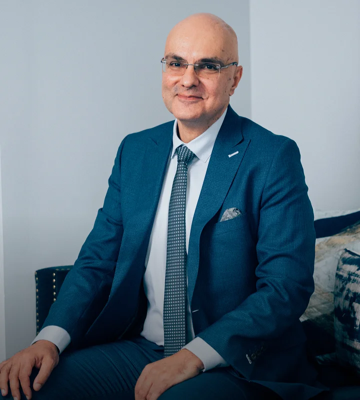 A professional portrait of Dr. Papafragkou, wearing a blue suit, white shirt, and patterned tie, sitting comfortably in a well-lit office.
