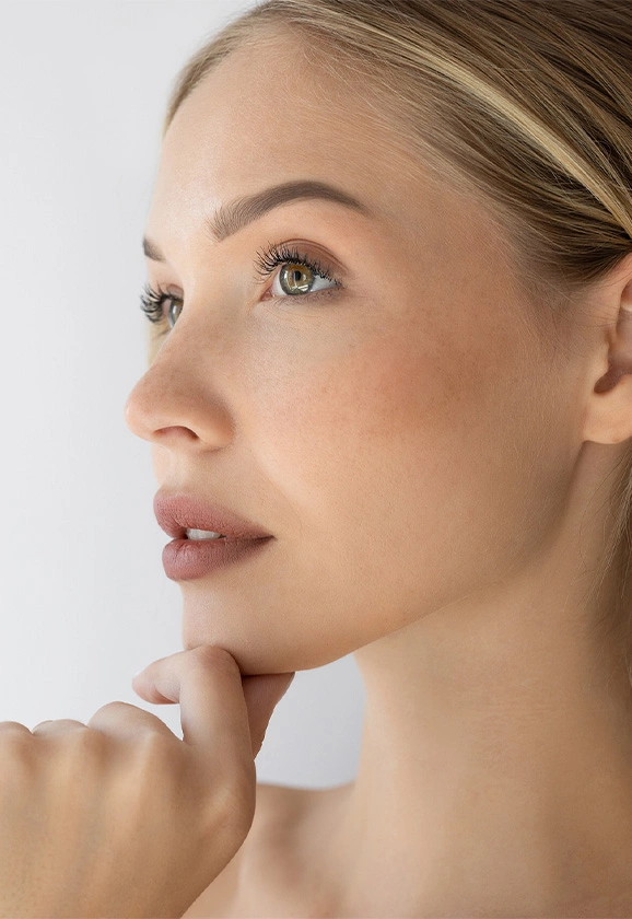 A profile view of a woman with blonde hair pulled back, looking upward and highlighting her jawline.
